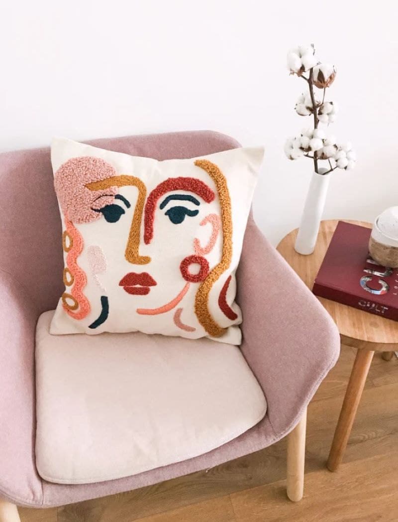 Hand-embroidered abstract face on white pillow