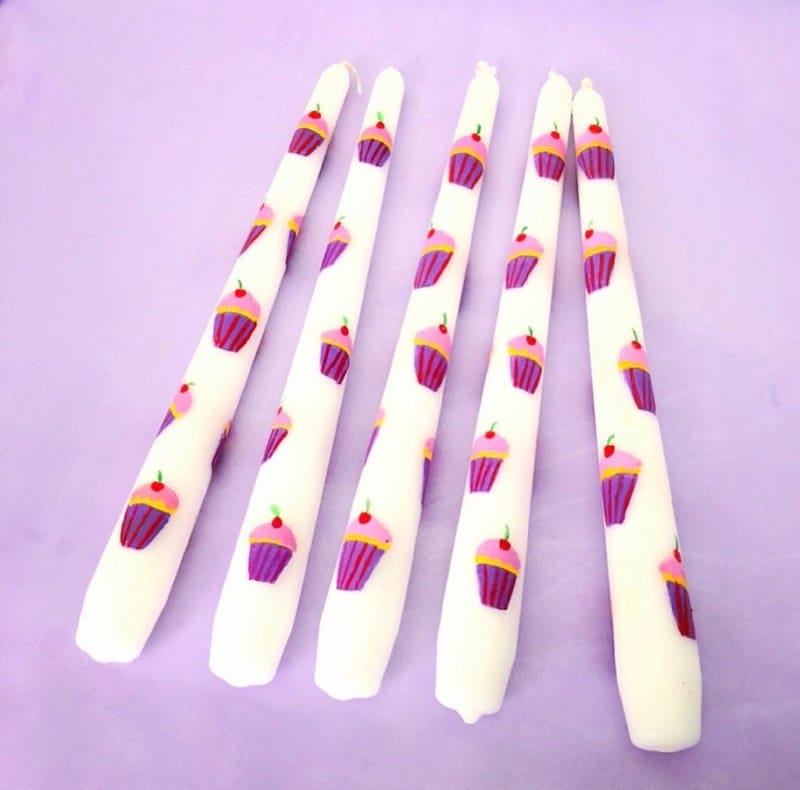 Five tall tapered candles hand-painted with cupcakes on them.