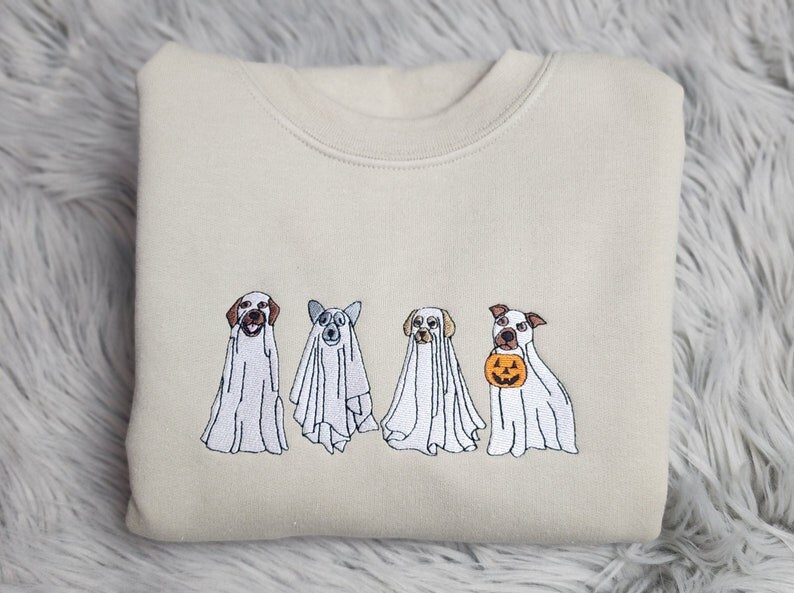 A folded cream sweatshirt featured embroidered dogs dressed as ghosts for Halloween.