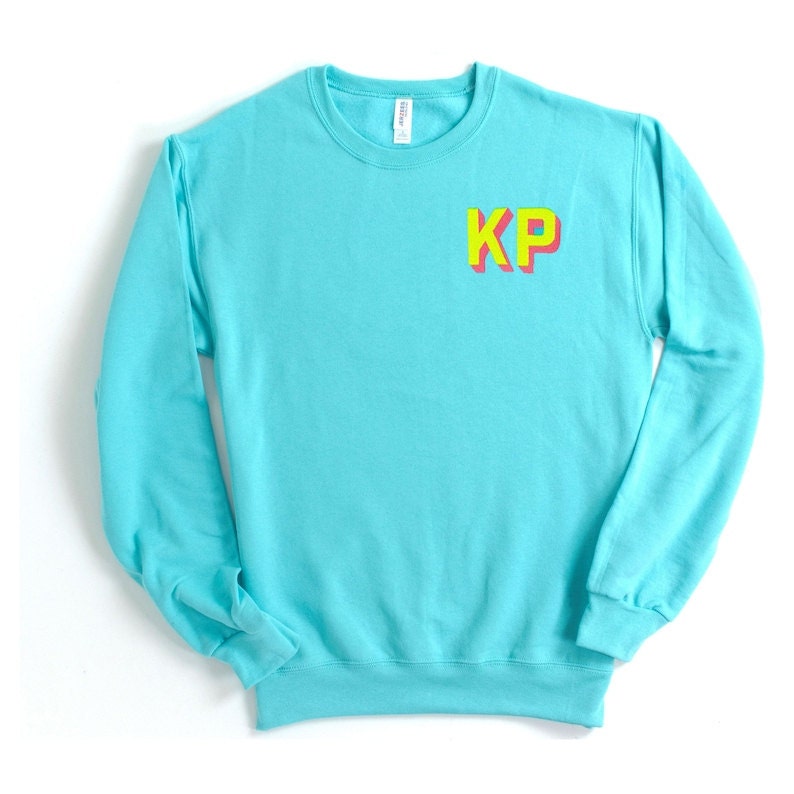 A neon blue crewneck sweatshirt with monogrammed block letter initials.