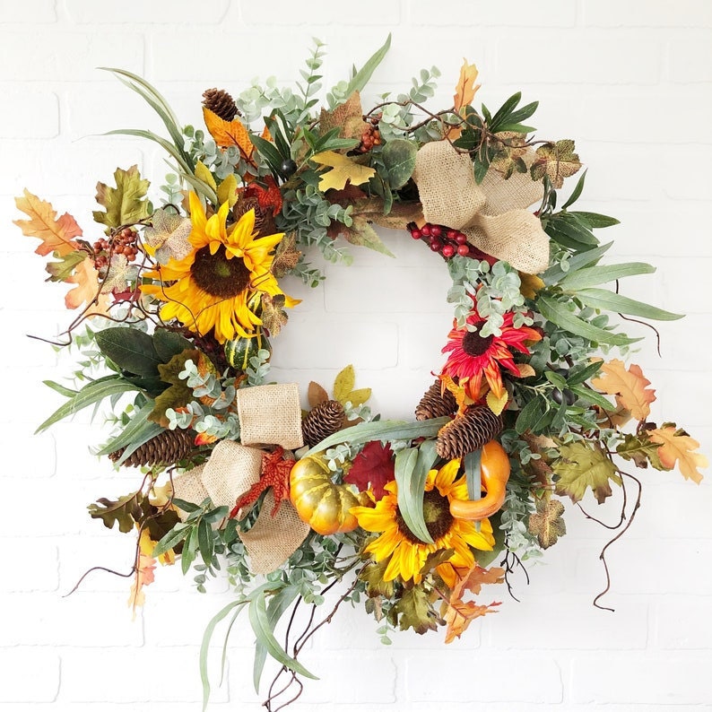 A traditional fall wreath featuring sunflowers and pumpkins.