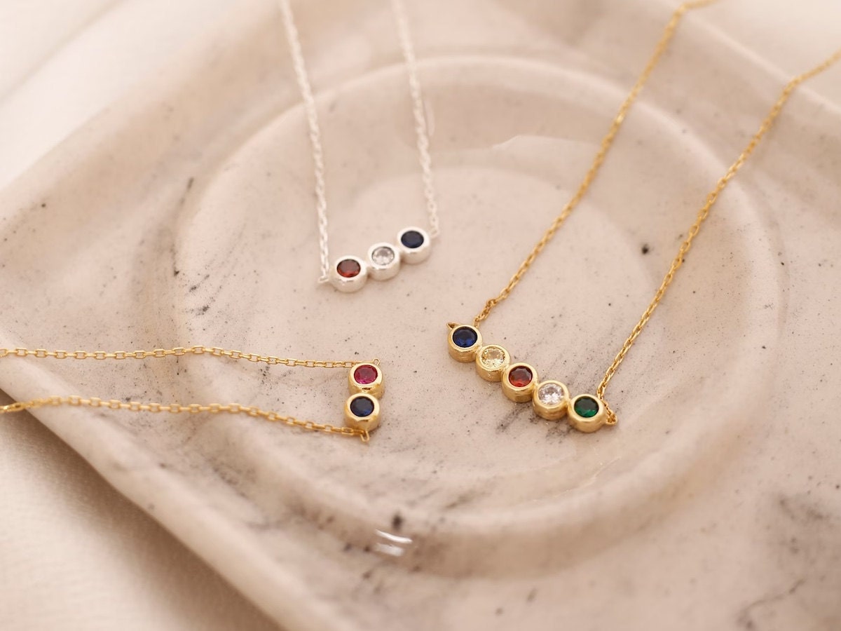 A set of three birthstone necklaces resting on a marble tray. A set of three birthstone necklaces resting on a marble tray.