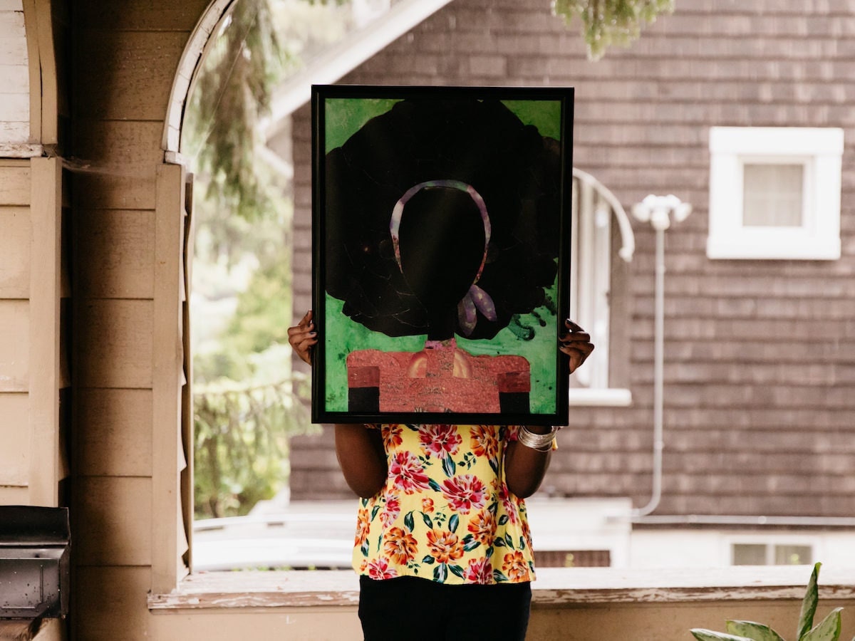 Mirlande Jean-Gilles standing on her Baltimore front porch, holding one of her pieces.