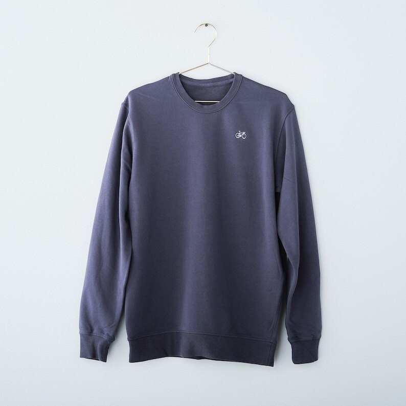 A dark blue crewneck sweatshirt featuring a tiny bike embroidered in the top corner.