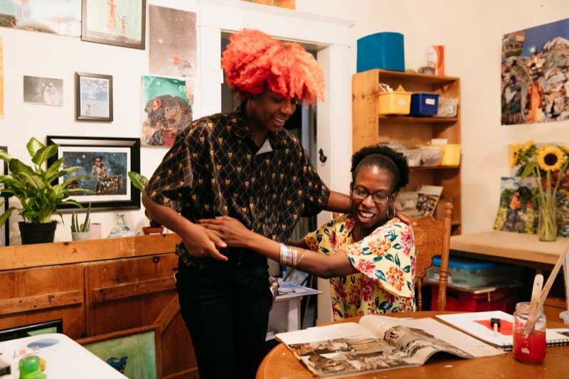 Mirlande embraces her daughter at her dining room table.