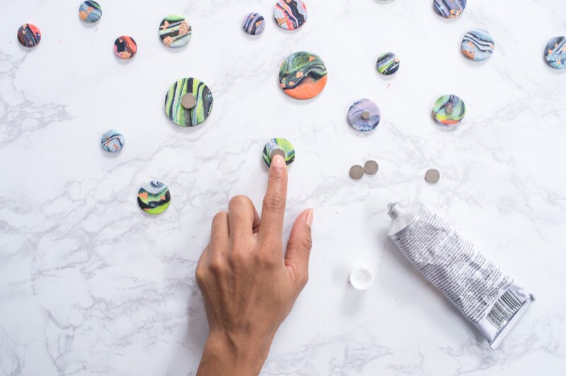 Hands gluing magnets onto shapes. Hands gluing magnets onto shapes.
