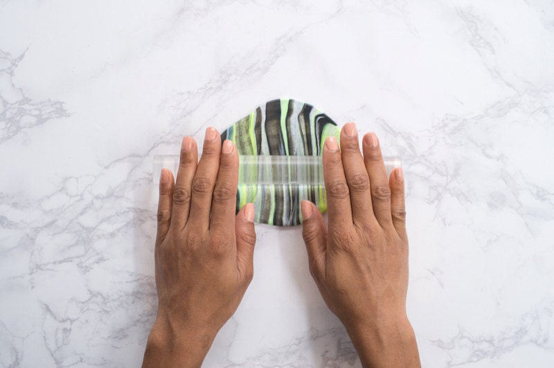 Hands rolling the strand out with a rolling pin so that it's flat against the marble background. Hands rolling the strand out with a rolling pin so that it's flat against the marble background.