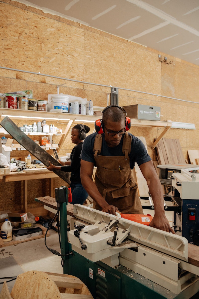 Kwadwo and Faith working in the woodshop, both wearing over-the-ear ear protection