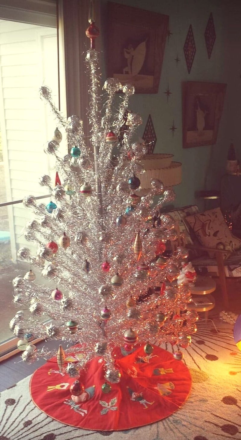 A vintage aluminum Christmas tree with ornaments on it.