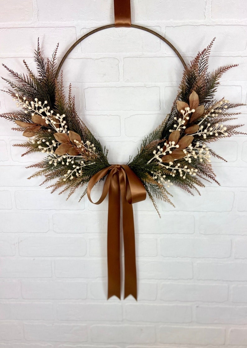 A boho-inspired fall hoop wreath featuring white berries and a brown ribbon.