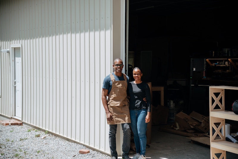 Portrait of Kwadwo and Faith posing outside their open studio door