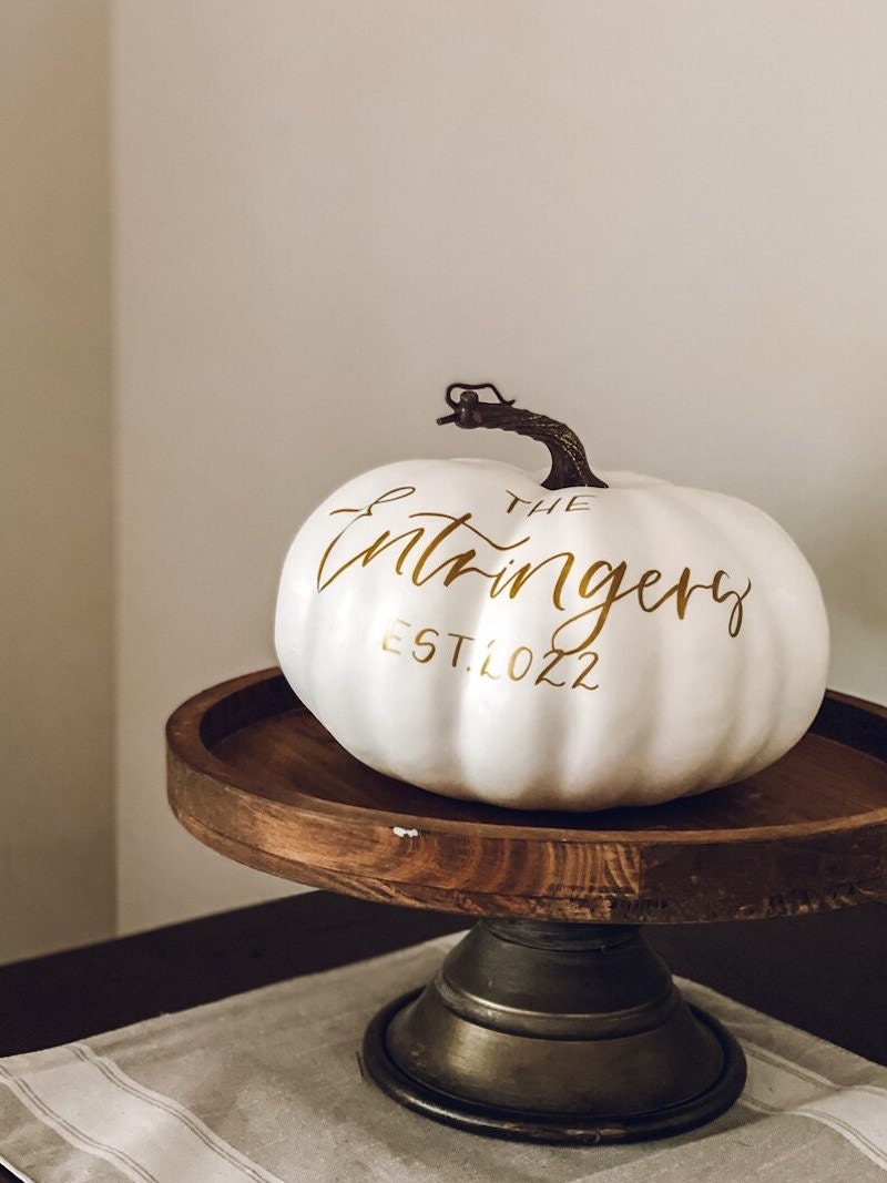 A hand-painted cream fall pumpkin with a family name and year established on it.