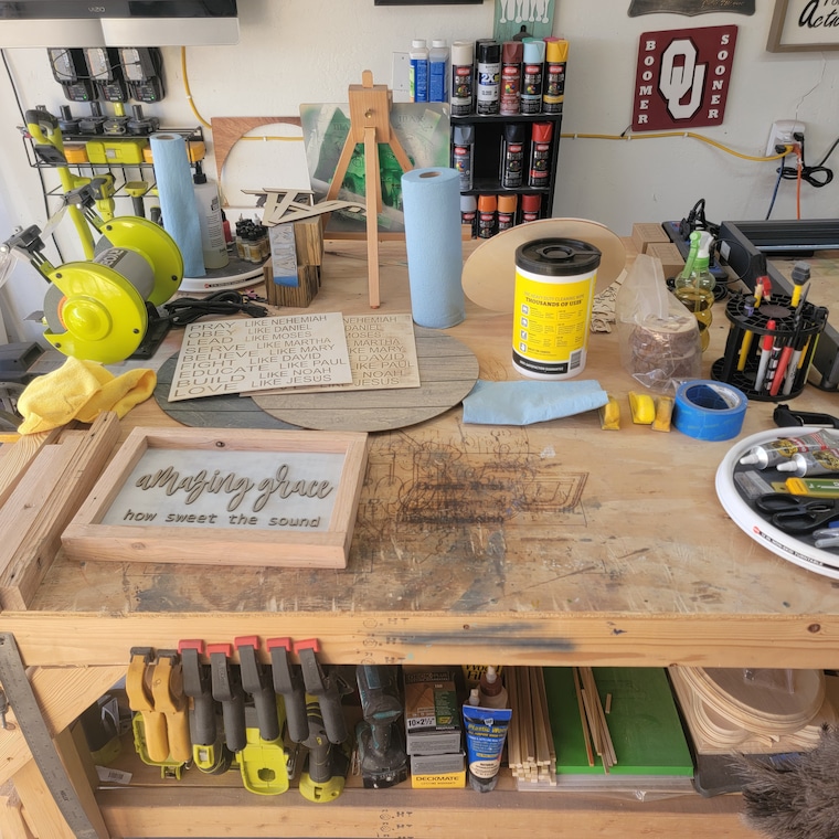 A workbench with paints, clamps, and other tools for making decor and signs.