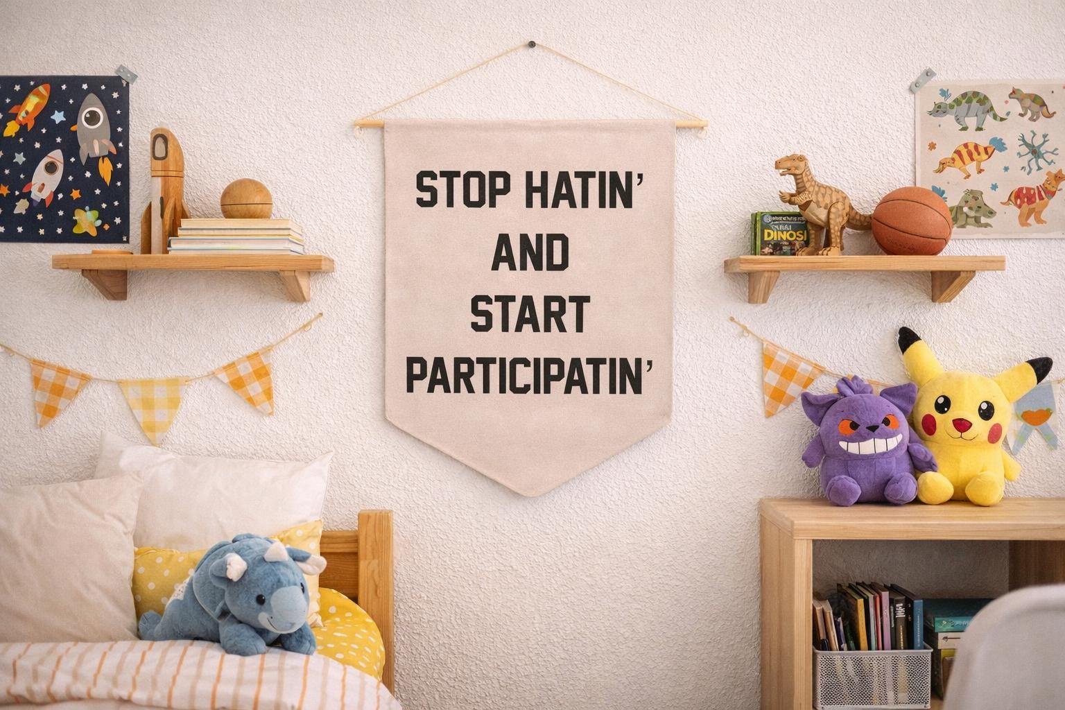 A cheerful, playful kids bedroom with a light textured wall. A cream felt pennant banner reading STOP HATIN AND START PARTICIPATIN in bold black letters hangs from a wooden dowel at the center. Yellow and white gingham bunting garland is draped across the wall on both sides. On the left, a wooden wall shelf holds a space-themed canvas print with rockets and stars, books, a wooden toy, and a round ball. On the right shelf sit a plastic dinosaur figure, a basketball, a book titled Dinos!, and a colorful dinosaur poster. A low wooden bookcase on the right holds Gengar and Pikachu Pokémon plush toys on top, with books and a wire organizer below. In the lower left, a childs bed with a wood frame features yellow striped bedding, a yellow pillow, and a blue triceratops stuffed animal.