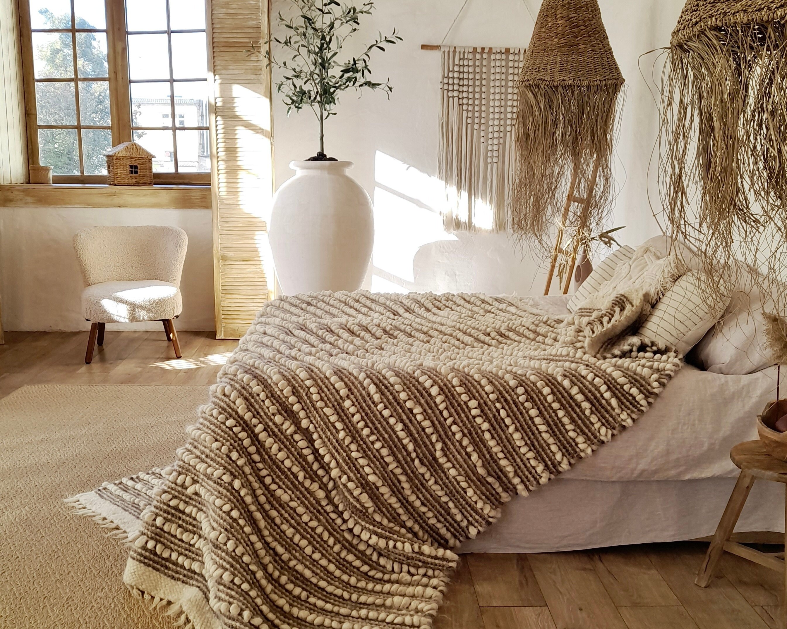 Scandinavian bedroom with white walls, minimalist furniture, and a cozy knitted blanket