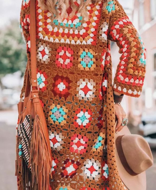 Woman wearing a Crochet Granny Square Coat and holding a hat with a bag over her shouder