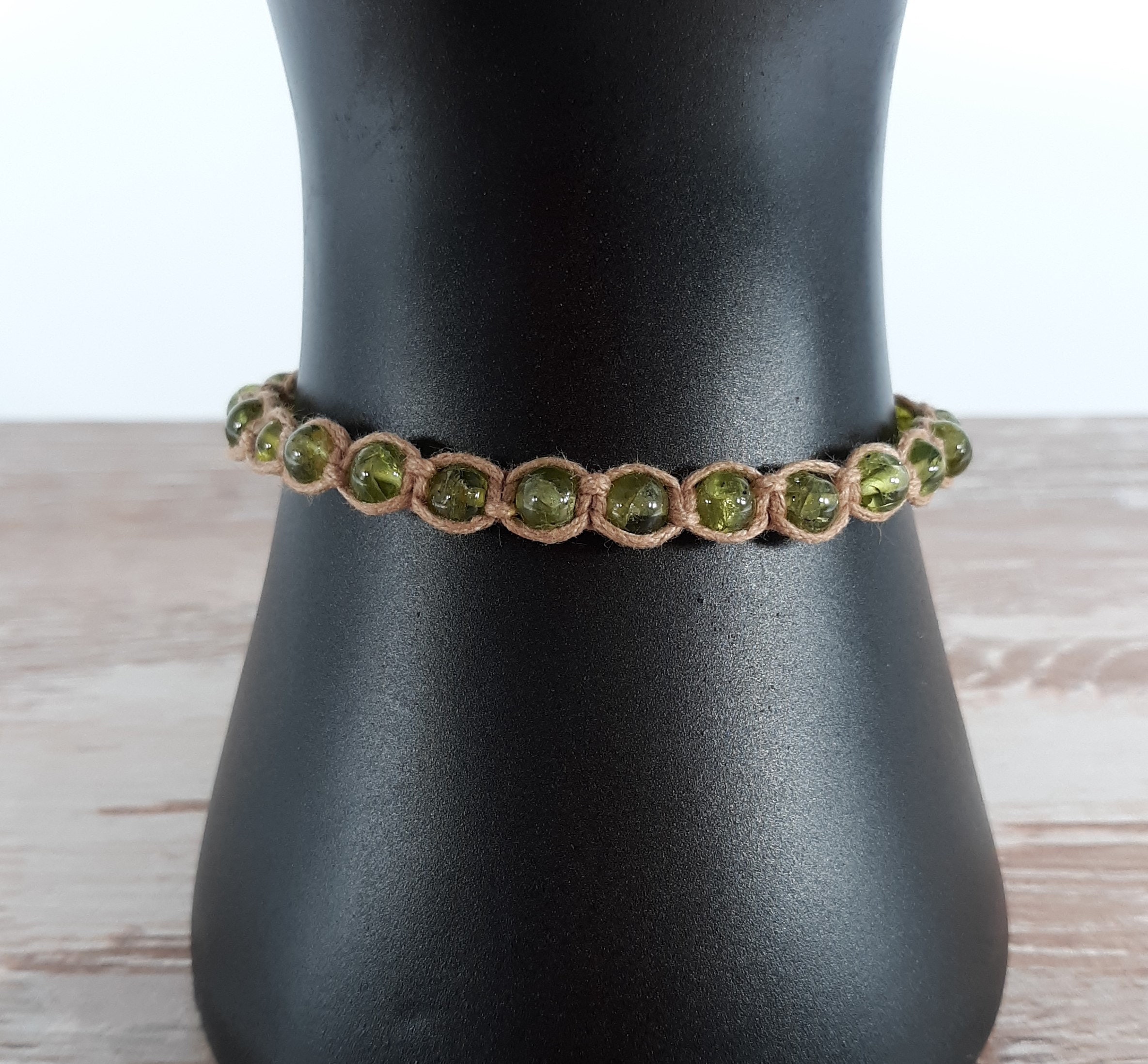 green peridot with many inclusions knotted onto beige cotton cord