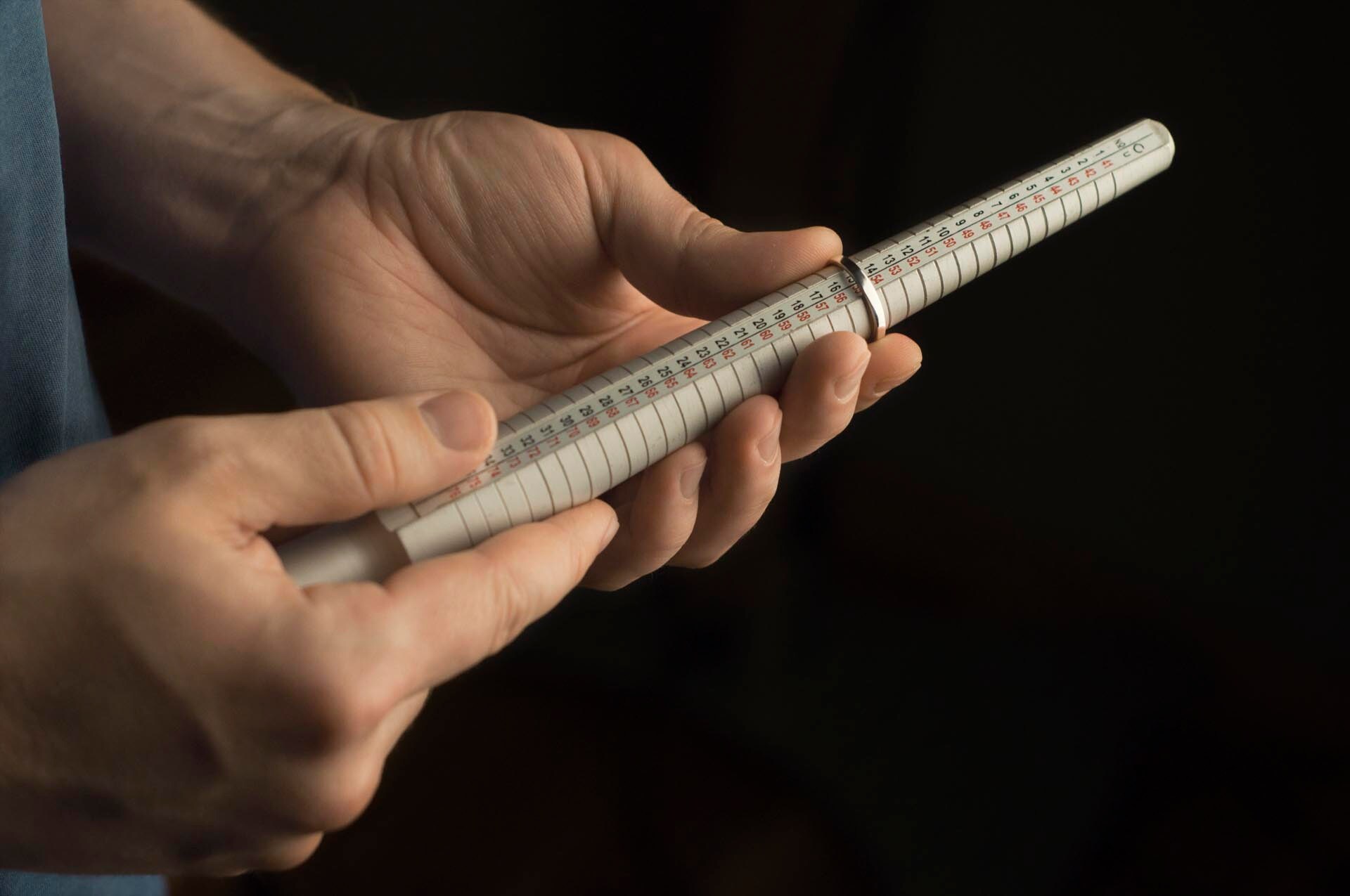 A goldsmith using a ring stick/mandrel to determine the rings size