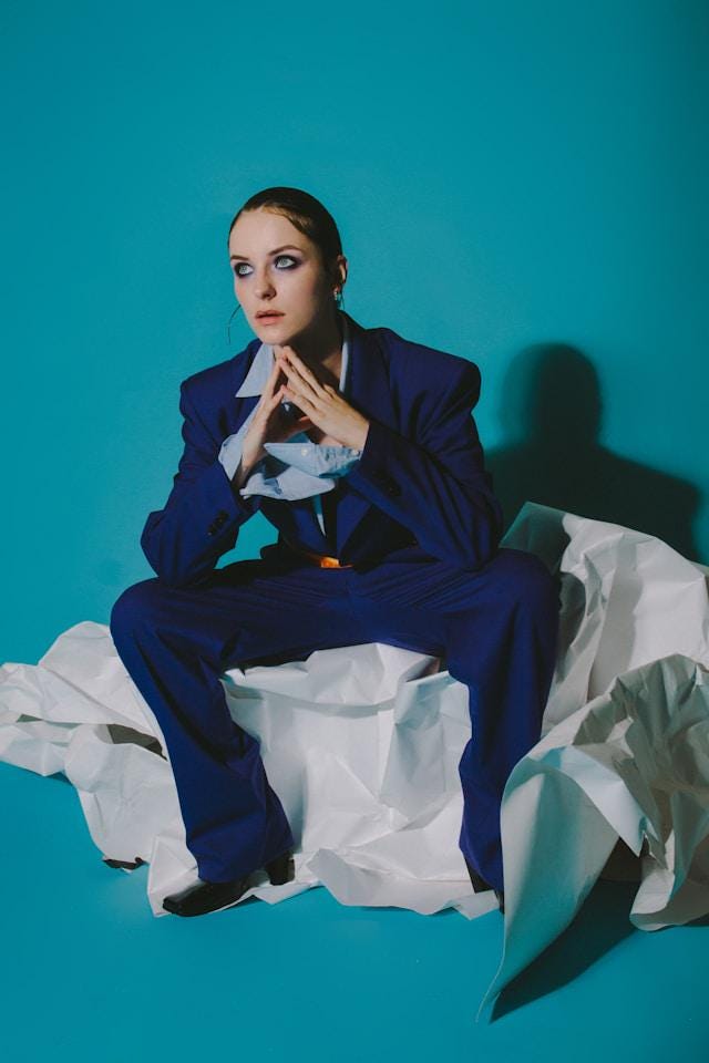 Blue fashion image of model posing with serious look in here eyes. Blue suit and blue backround.