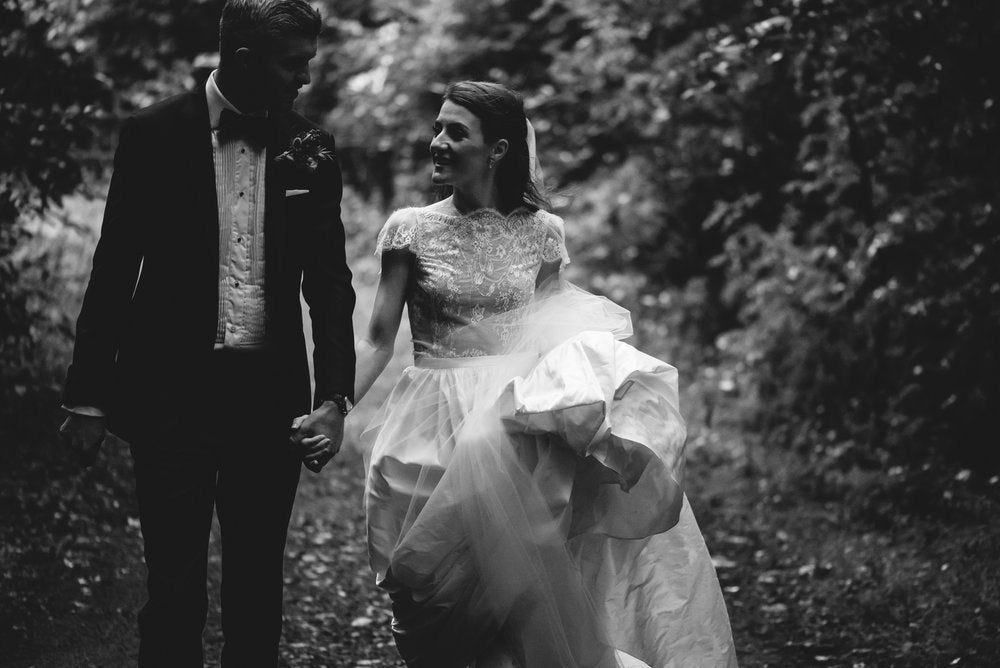 Black and white photo of the bride and groom walking in gardens or lush scenery