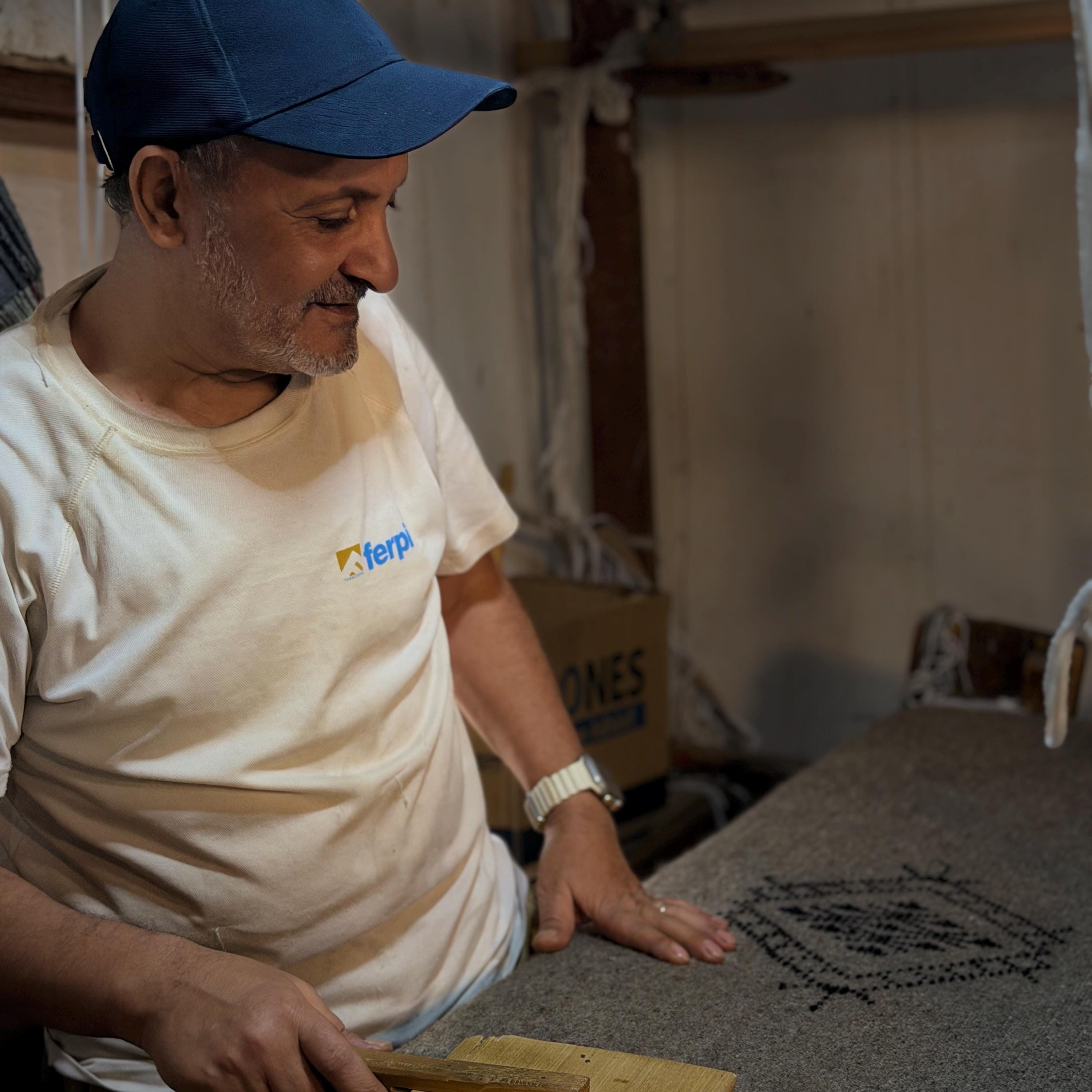 Figure 12. Pressing the weave with a wooden mallet so the cloth sits dense and even.