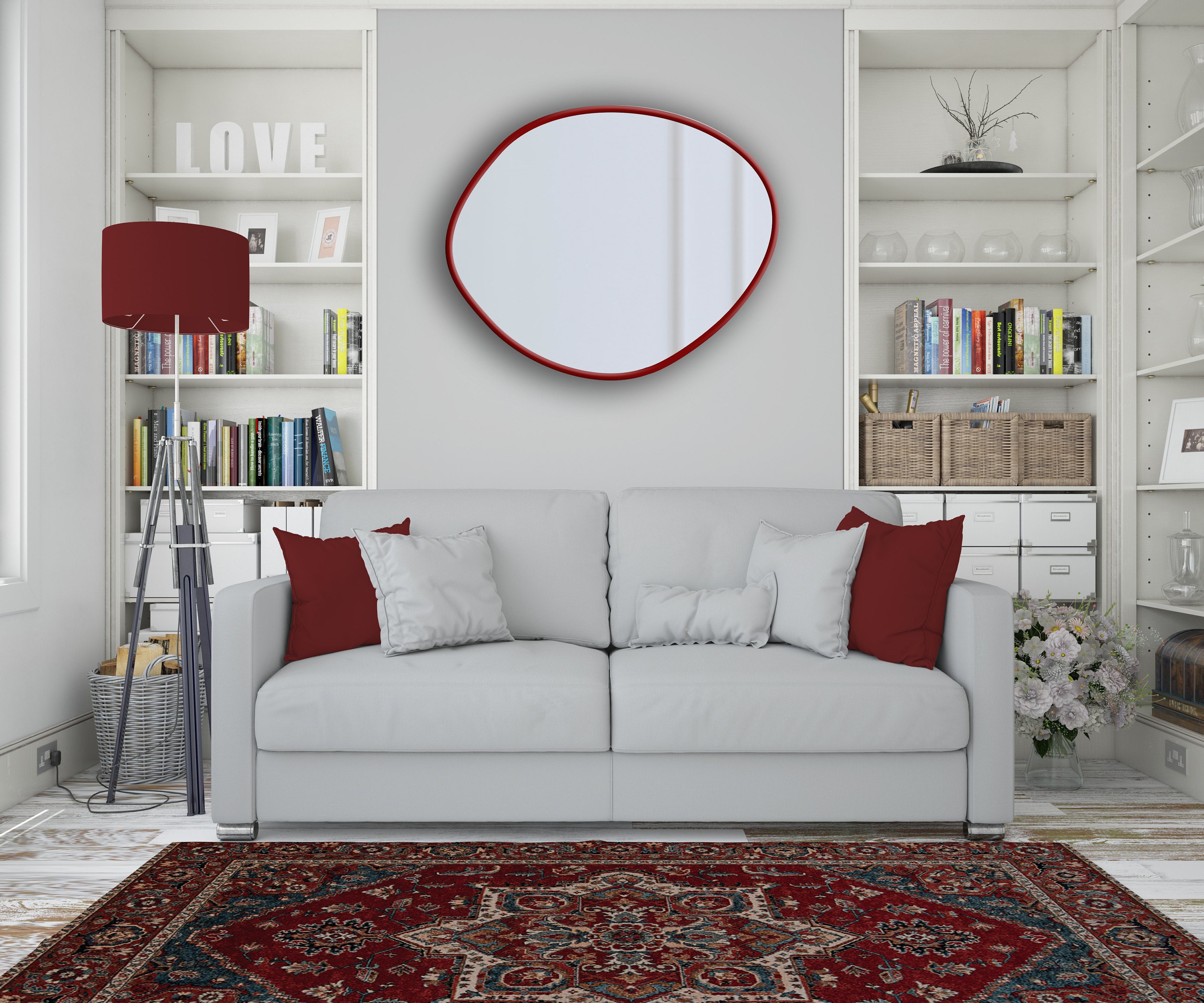 Red frame asymmetrical mirror hung on the wall of a living room above a couch and with red home decor accessories such as red oriental rug.