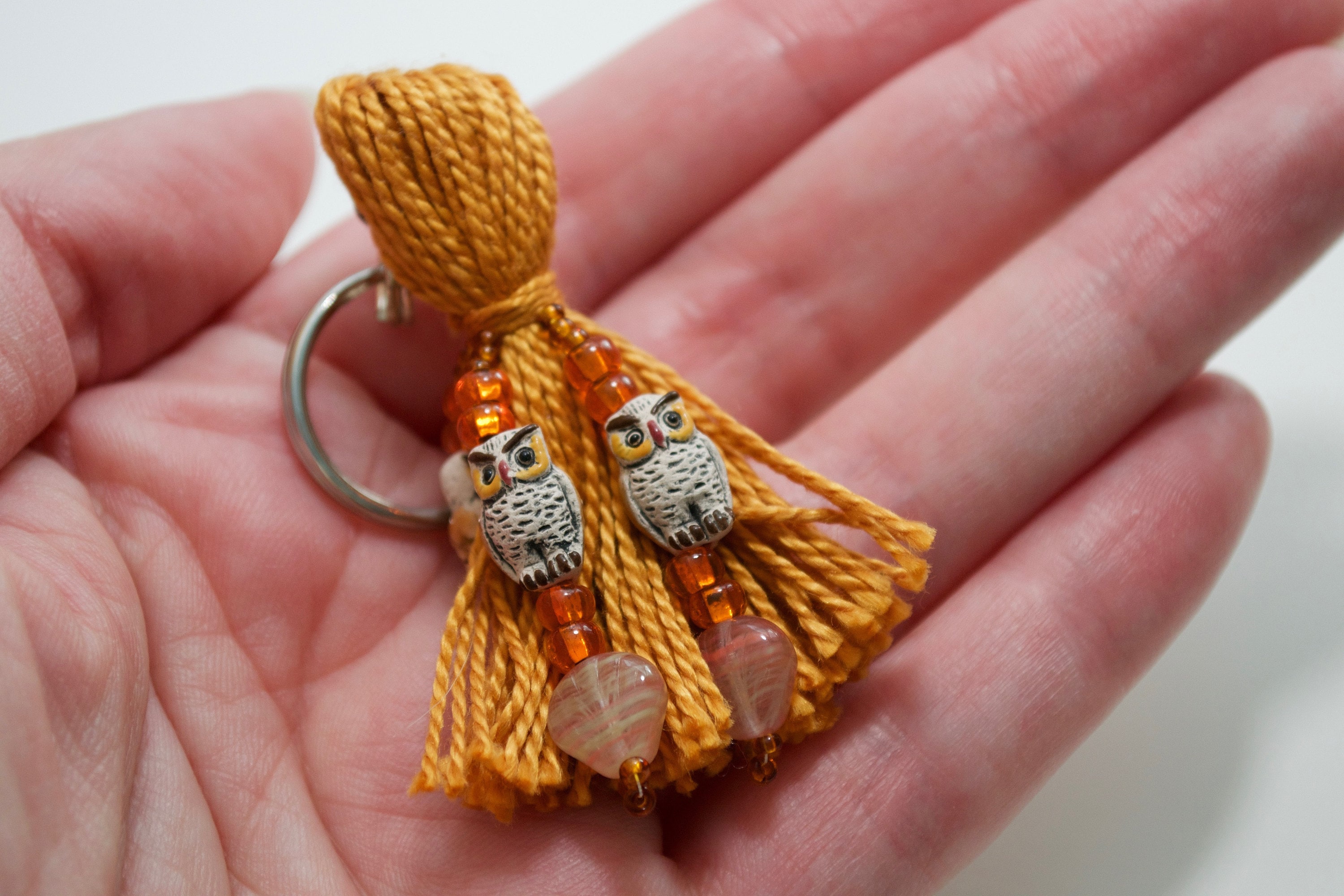 Brown owl beaded tassel keyring, held in hand