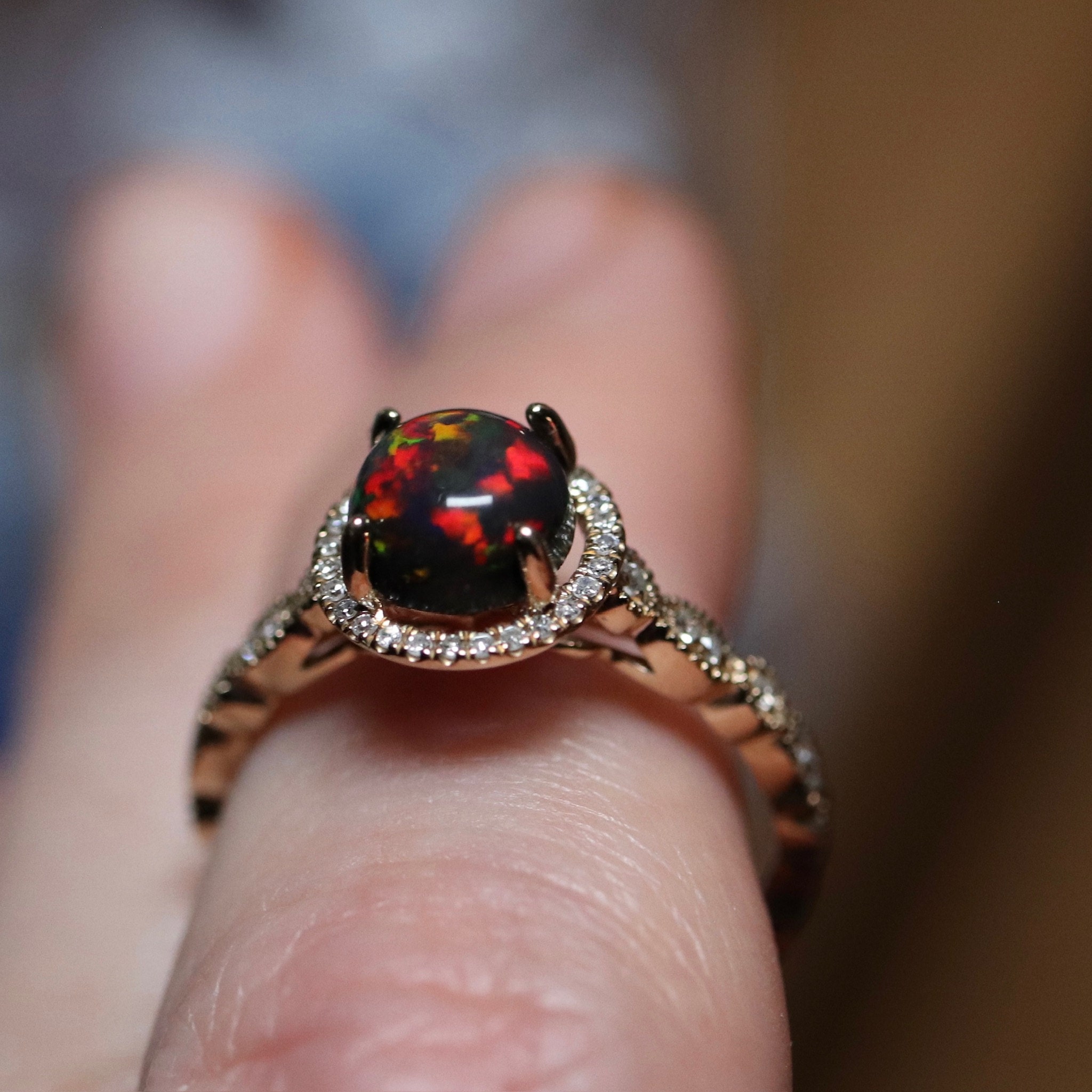 Gold ring with a black opal in the center with diamond paved halo