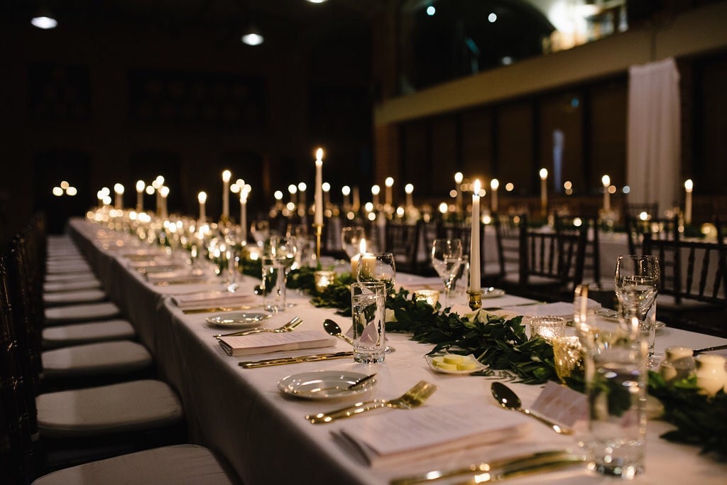 Photo of evening wedding table with candle holders, foliage and calligraphy menus