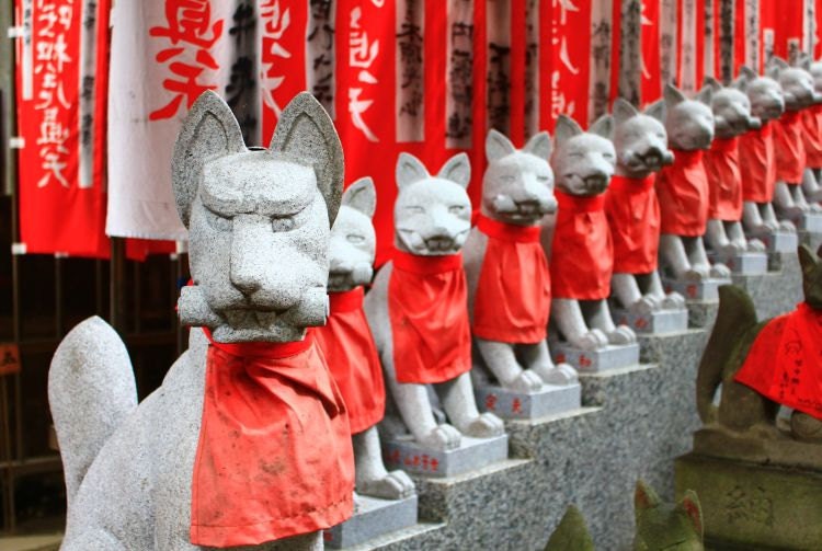 Rangée statues renard pierre bavoir rouge