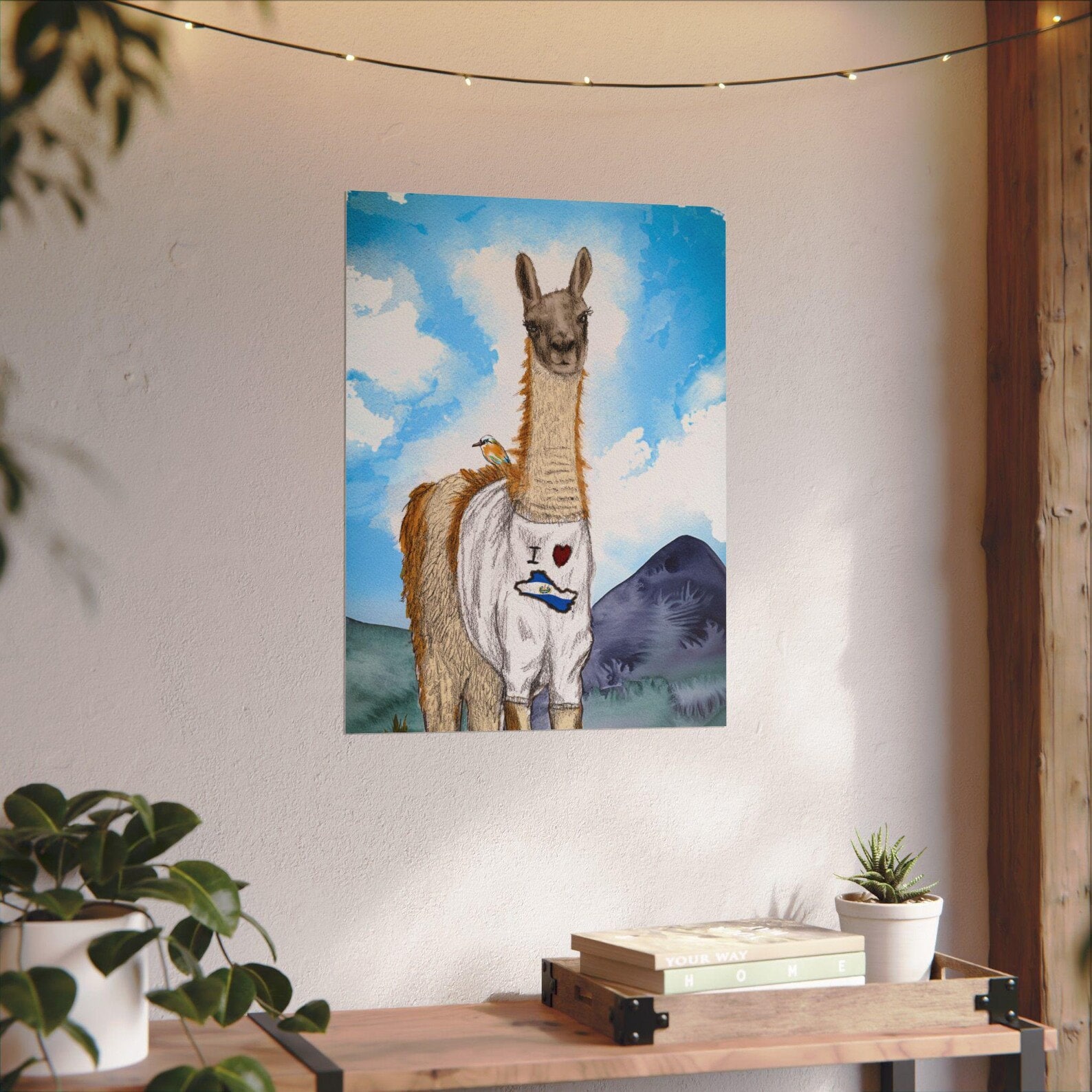 Poster of a drawring of the camelid Guanaco, wearing a T-shirt that says I heart El Salvador. The animal is similar to a llama.