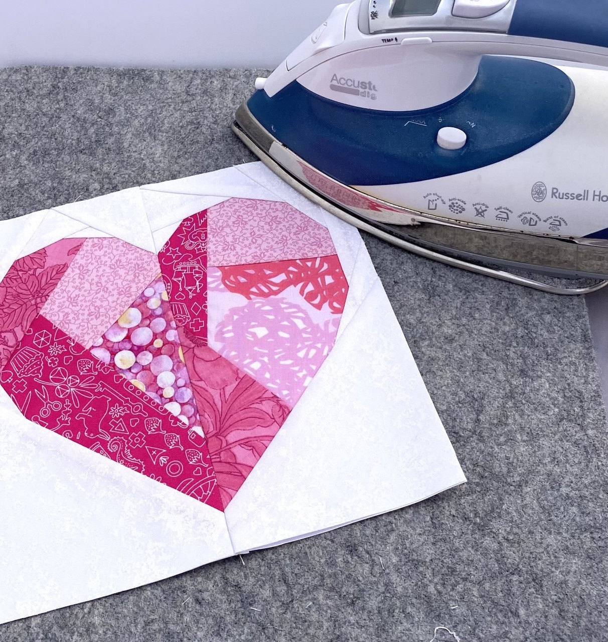 A beautiful foundation paper pieced heart being pressed by an iron before setting into a quilt.
