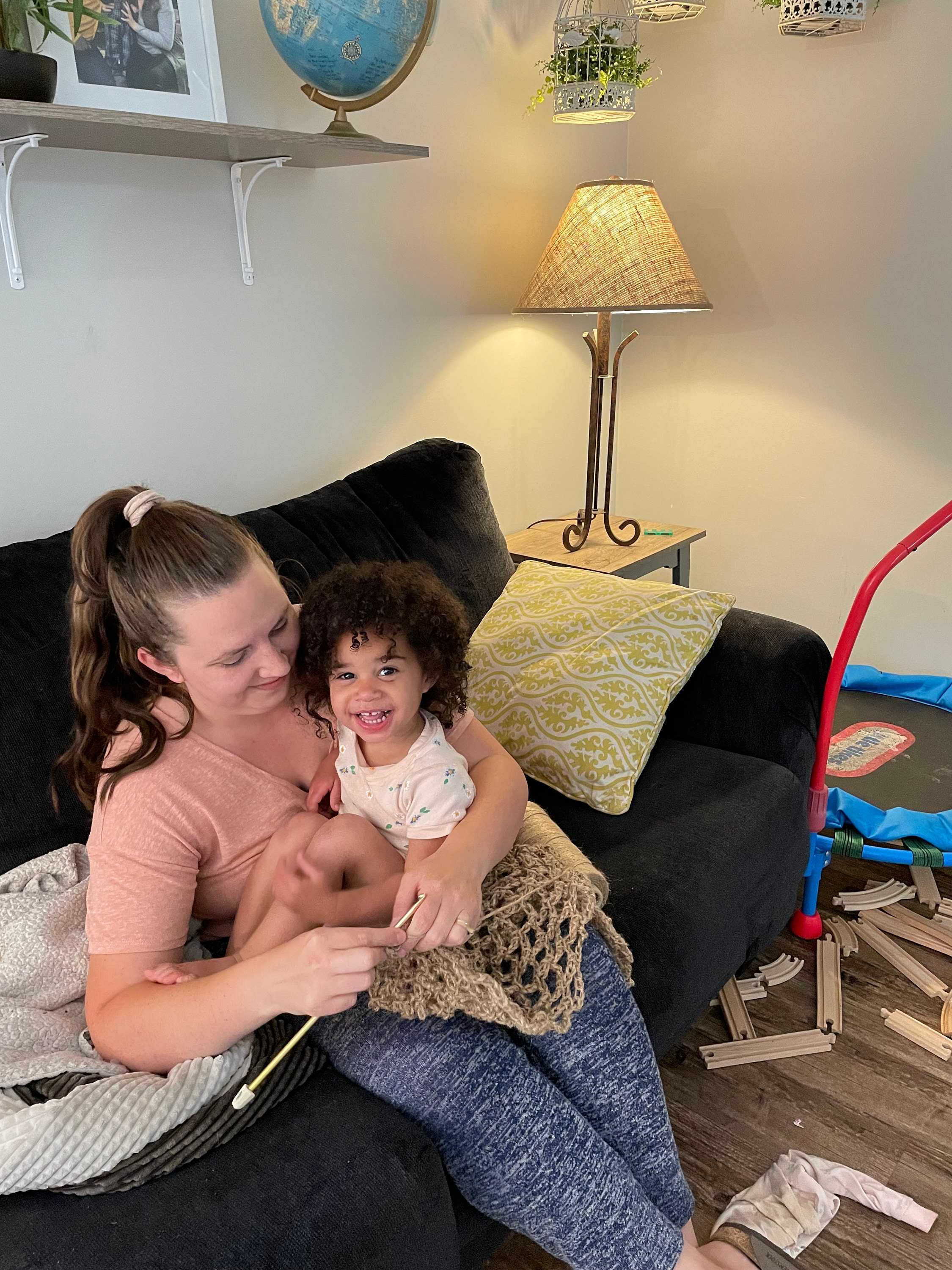 Woman crocheting while holding her toddler