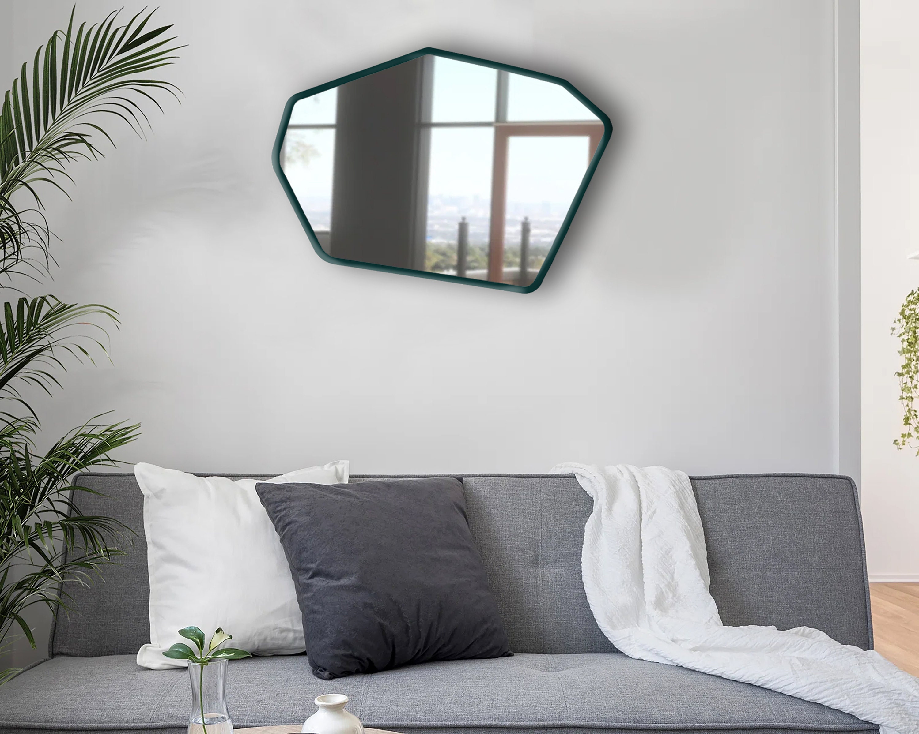 Edgy asymmetrical mirror hung on a living room wall above a couch.