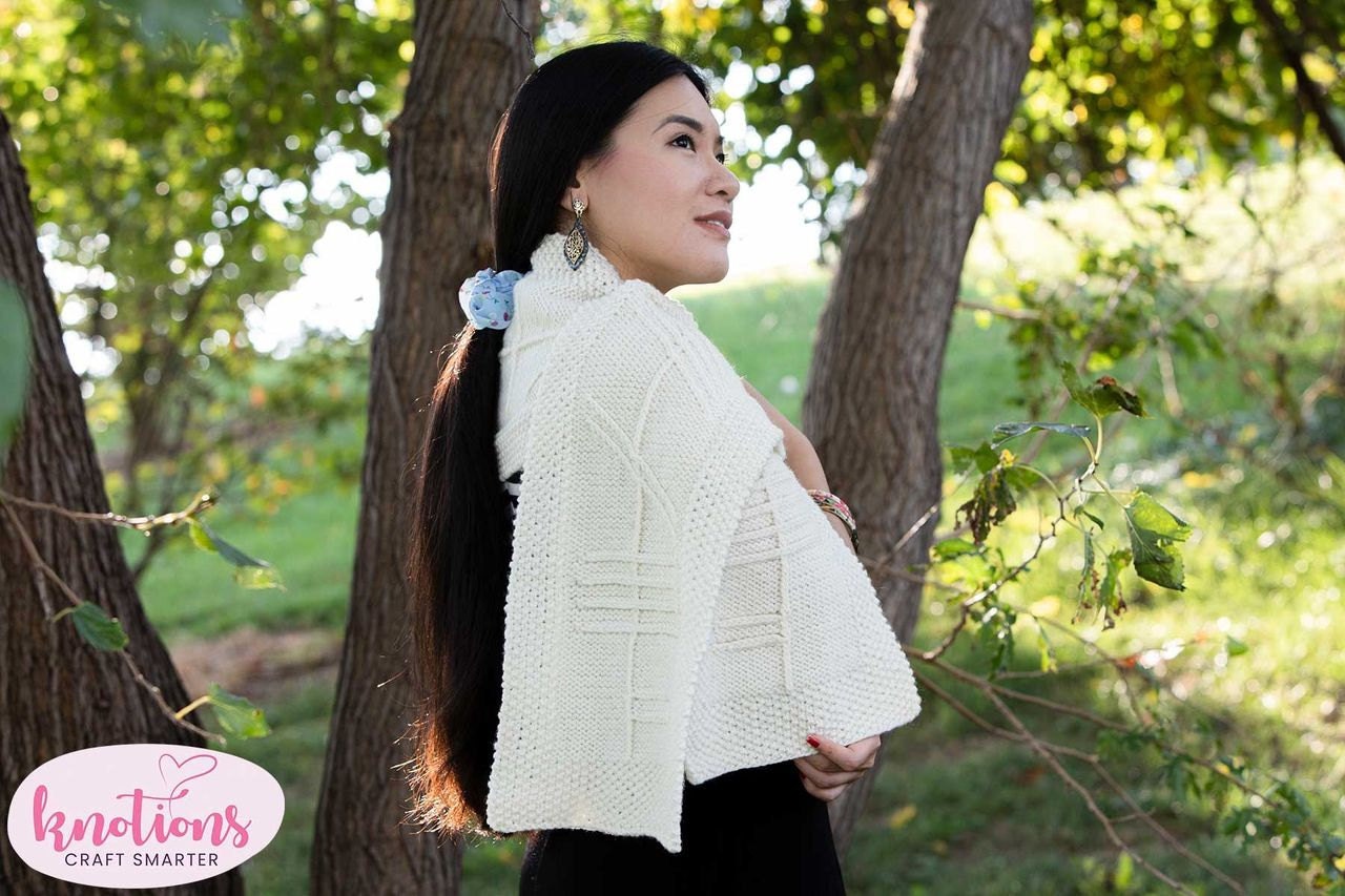 a woman looks off-camera; she wears a long white scarf with a linear pattern on it using the ancient Celtic language Ogham.