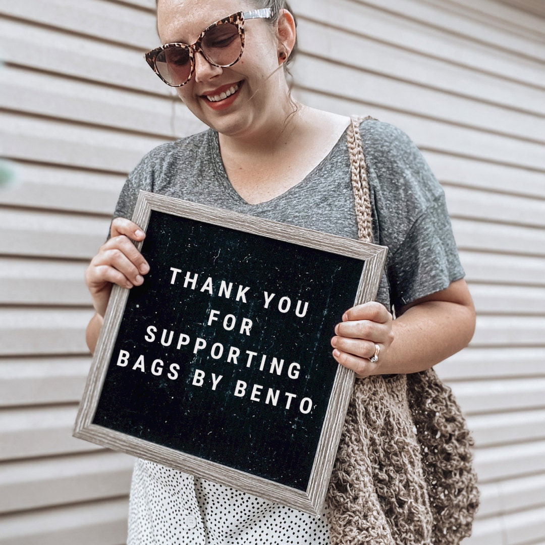 Woman holding a sign that says thank you for supporting Bags by Bento
