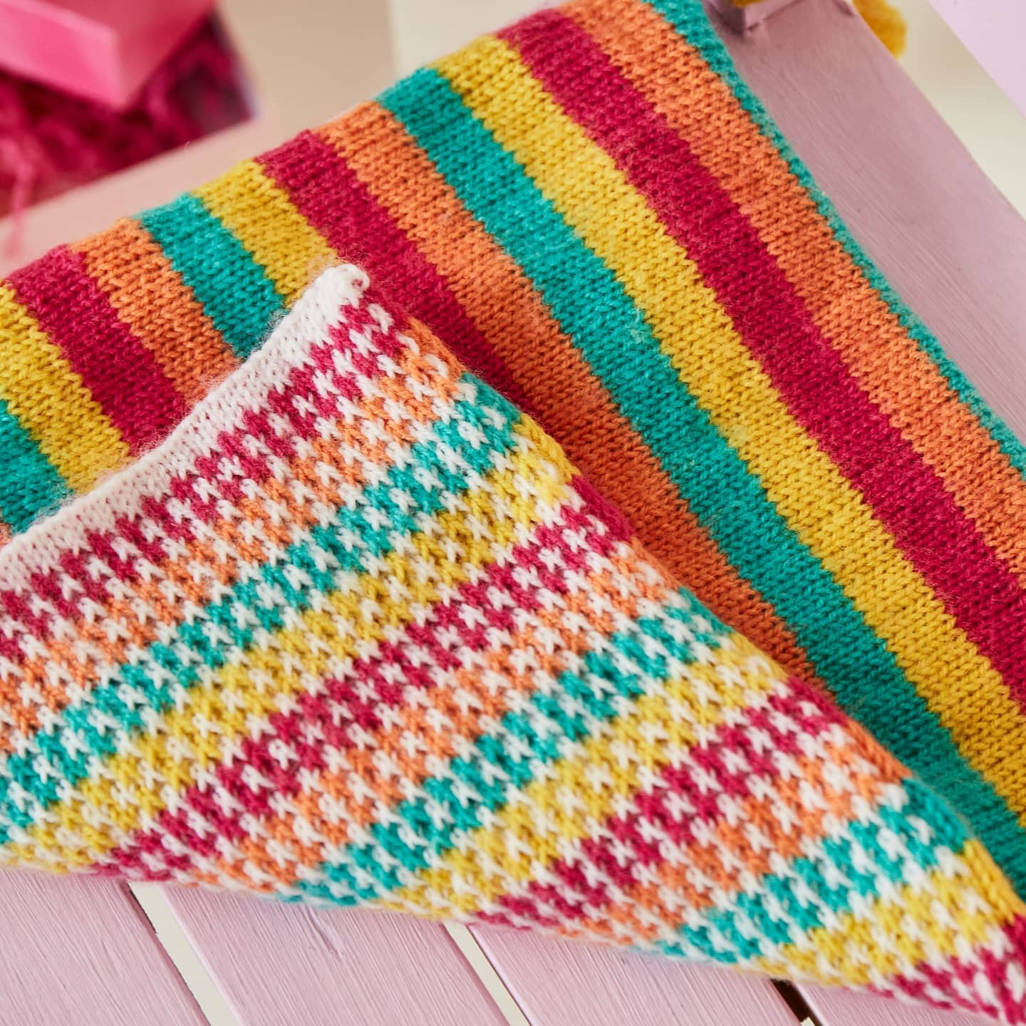 a colourful knitted seat pad corner is folded up to show that the striped design is reversible, and slightly different on both sides.