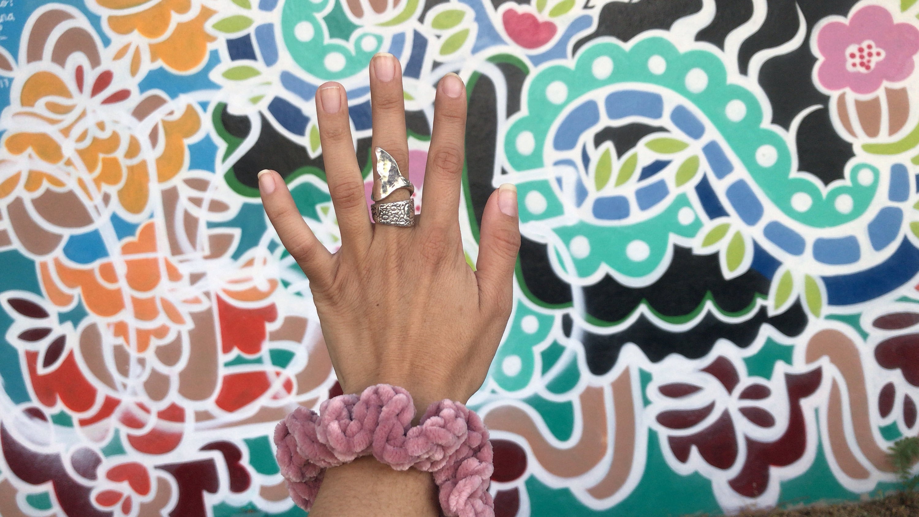 Mermaid ring by Avalonia Jewelry displayed against street art a Wynwood Walls Miami. Pink velvet scrunchy by Knot For U also featured.