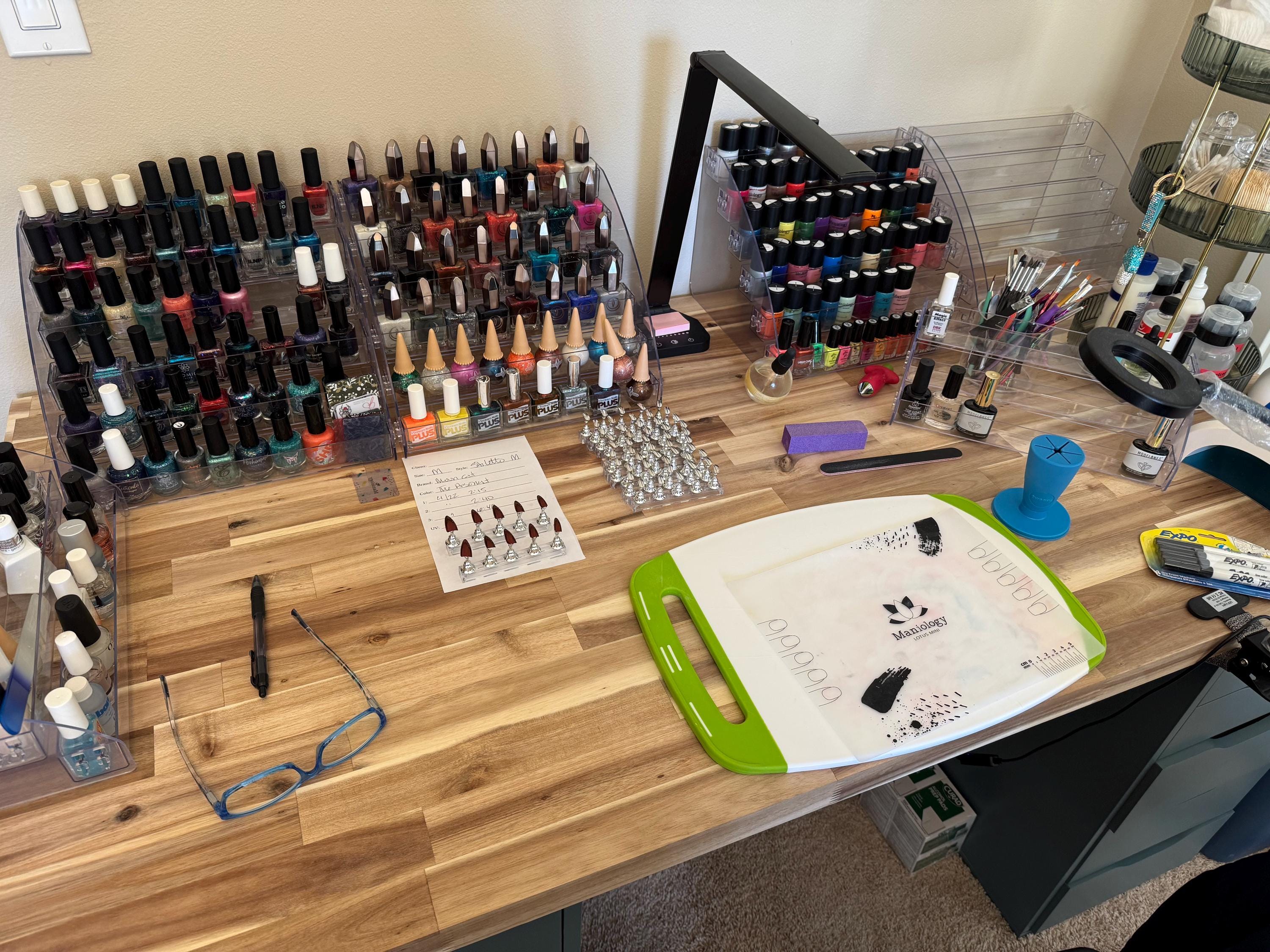 A fairly clean desk with a few racks of nail polish and some tools