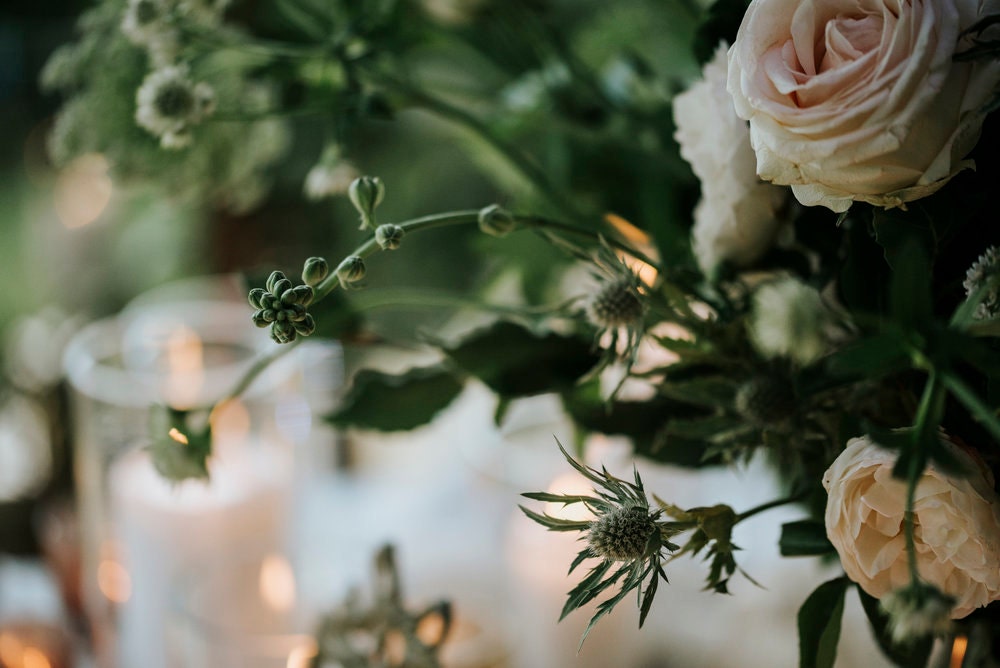 Blush flowers and green foliage with candle lights in the background