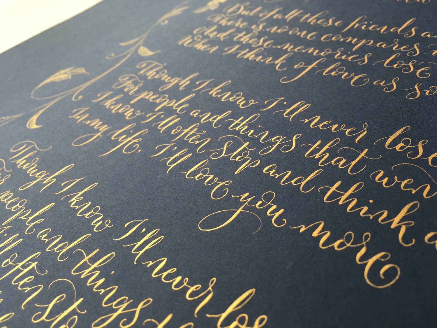 Modern calligraphy in gold ink on navy blue with playful flourishing