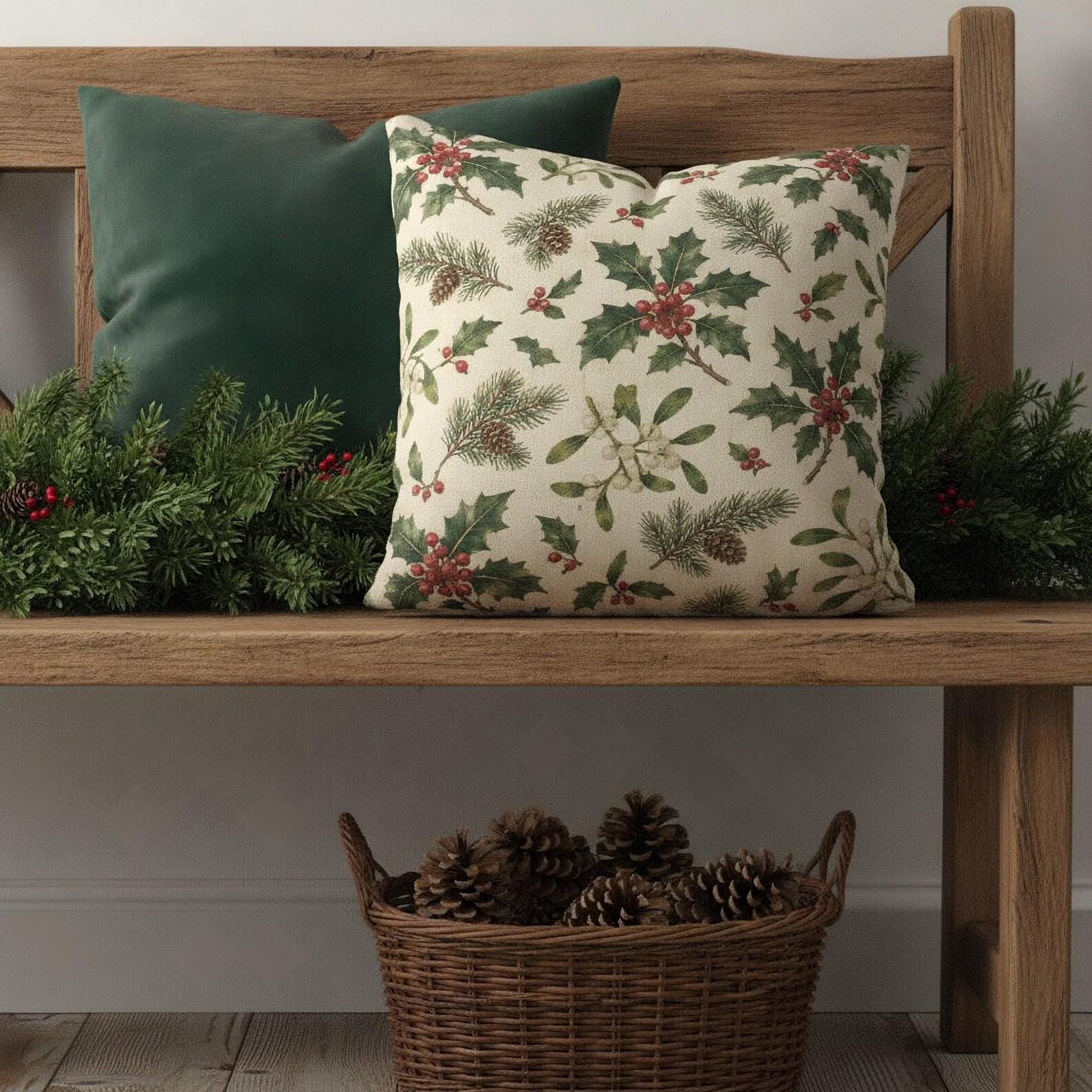 Vintage holly and berry Christmas pillow with a forest green pillow on a rustic wood entryway bench with pinecones