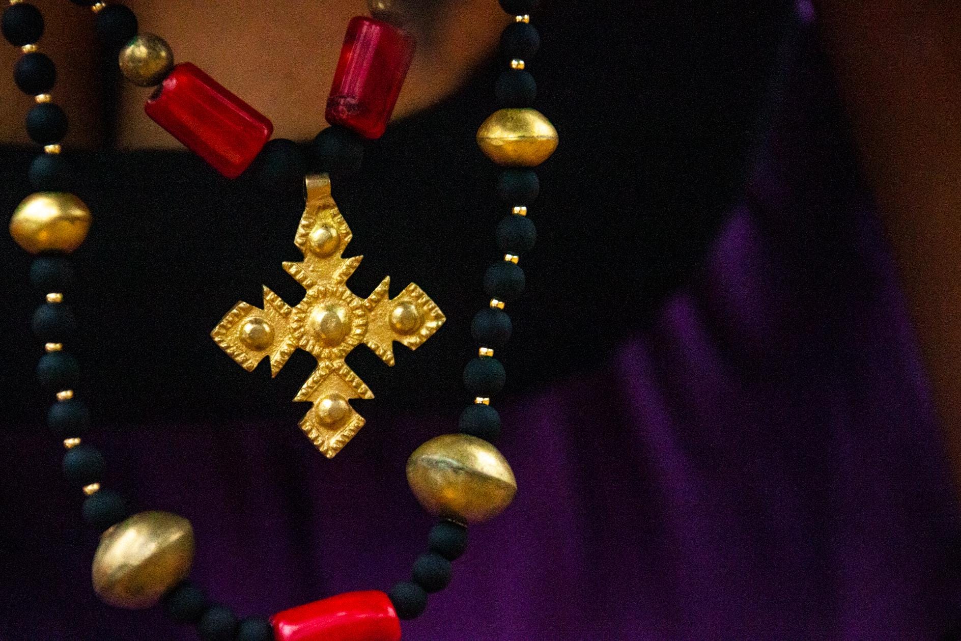 African beaded necklace with gold Coptic cross pendant, red glass beads, and black and gold accents