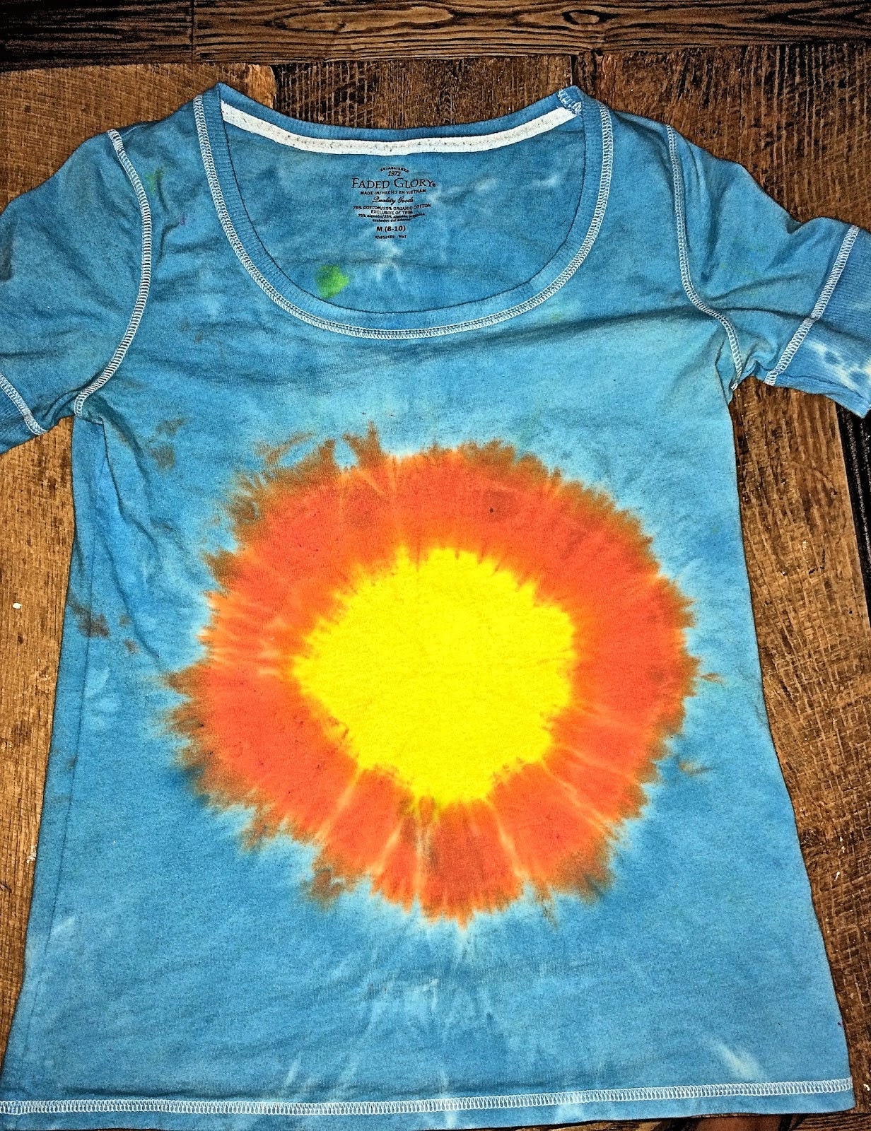 Finished sunburst tie-dye shirt after washing and drying — vibrant yellow, orange, and turquoise