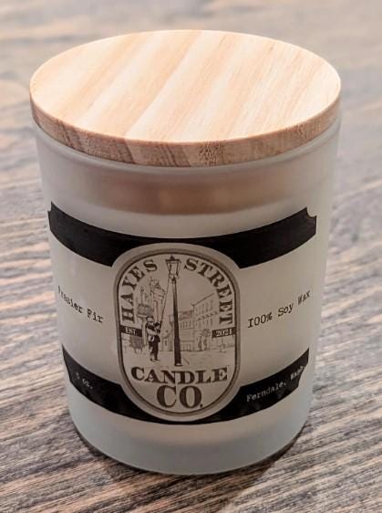 Frasier Fir 5 oz candle by Margie Creen. It is soy wax with no dye or additives. The candle in this picture is scented Frasier Fir and is in a small straight-sided jar with a bamboo lid. Hayes Street Candle Company candles are made by Margie Creen in her Ferndale, Washington, studio.