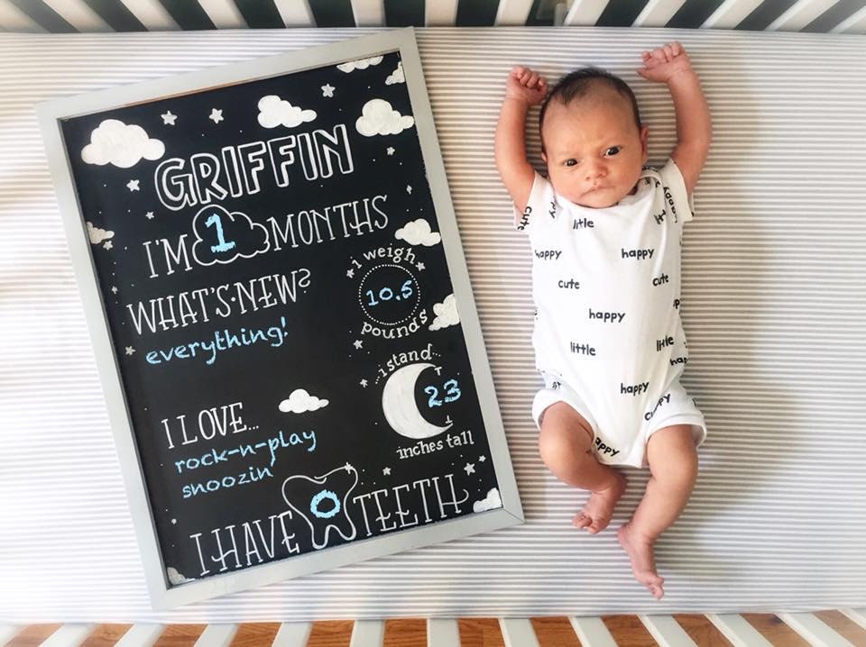 baby laying next to their milestone chalkboard