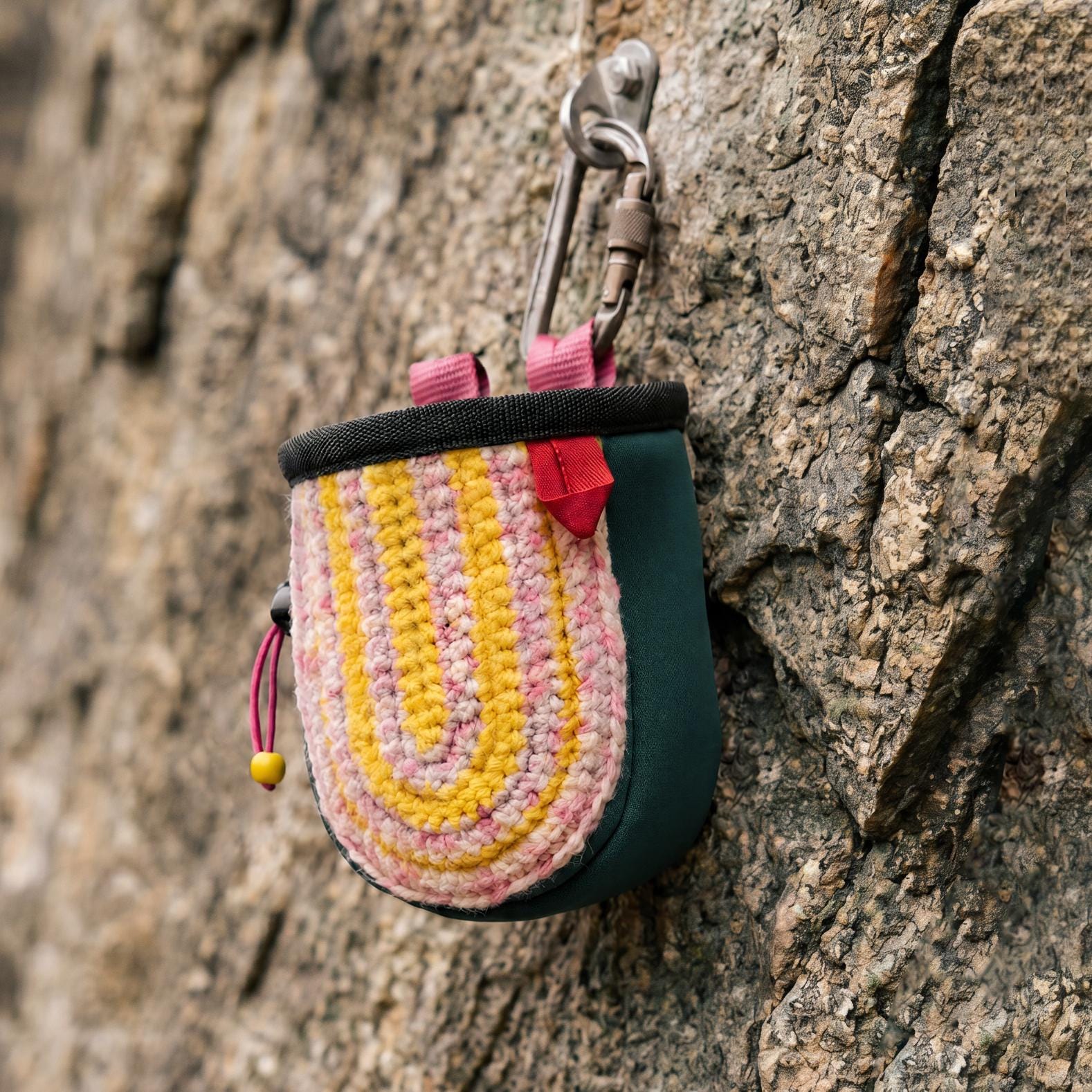 Hand-knit chalk bag with attachable harness in yellow and pink stripes by NadamLada, styled for rock climbing use.