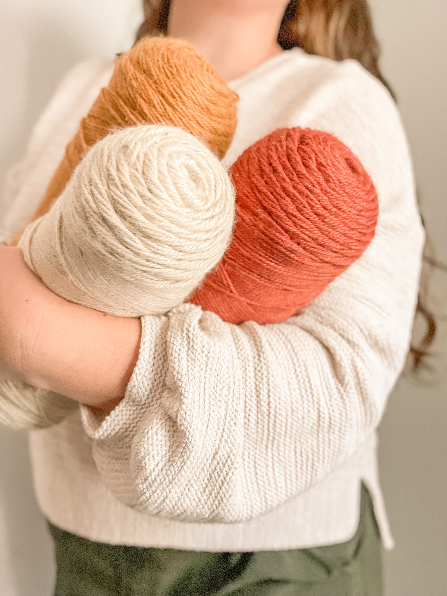 Woman holding three skeins of yarn in Fall colors