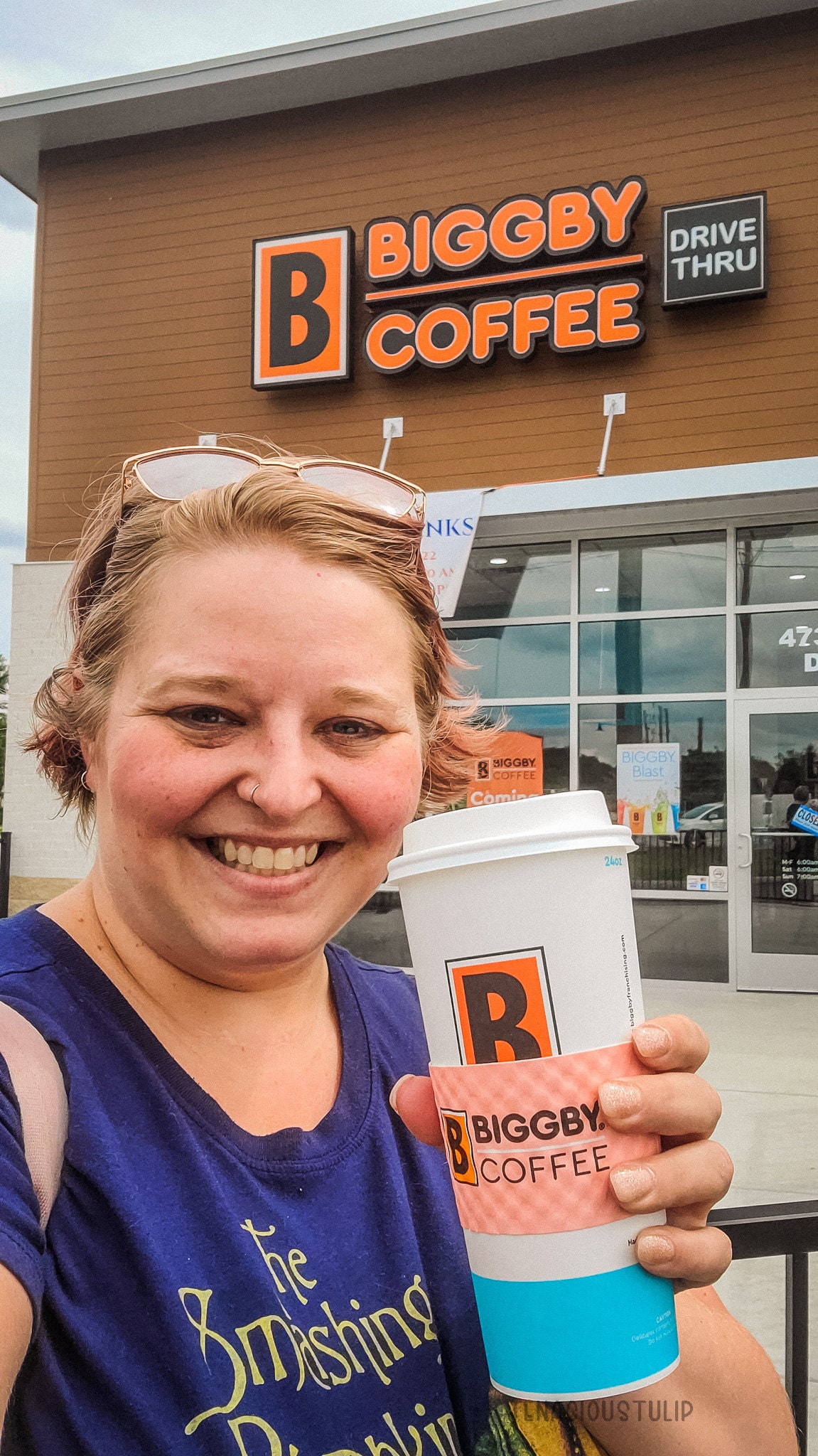 Woman holding a coffee cup in front of the coffee shop