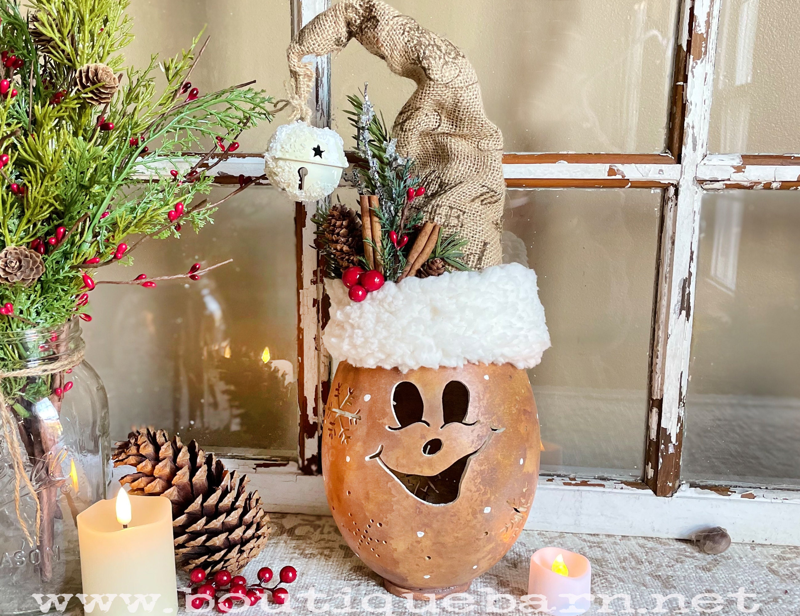 Handmade gourd decoration. A Christmas elf character with a carved face and snowflakes. Pip the elf wears a handmade elf hat made with burlap, Sherpa trim, and a white jingle bell.